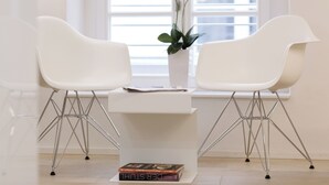 Una habitación moderna con dos sillas blancas, una mesa blanca y una planta en maceta.