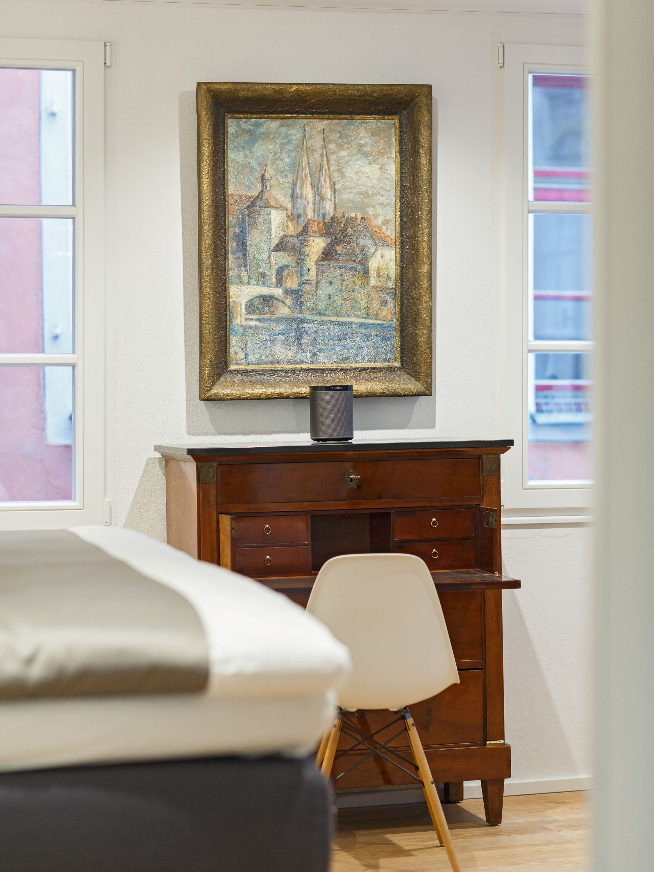 Een kamer met een houten kast, een stoel en een schilderij aan de muur.