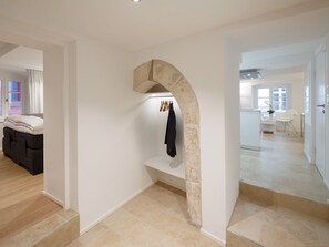 A modern interior with a stone archway, a seating area with a sofa, and a dining area with a table and chairs.