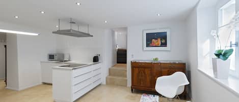 A modern kitchen with white cabinetry, a built-in microwave, and a stainless steel range hood.