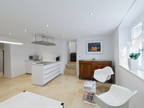 A modern kitchen with white cabinetry, a built-in microwave, and a stainless steel range hood.