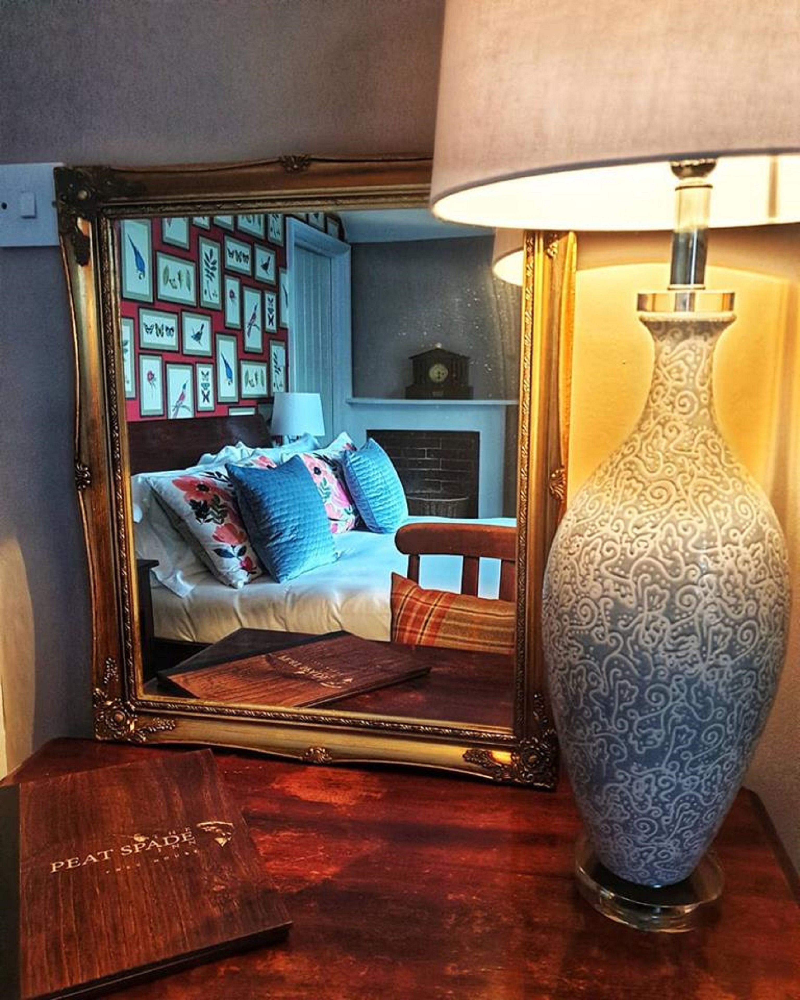 Un dormitorio con cama, almohadas, cómoda y espejo que refleja la habitación.