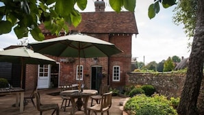 A brick building with a large umbrella patio area, outdoor seating, and a stone wall. - The Peat Spade Inn (Stockbridge)