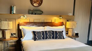 A neatly made bed with a wooden headboard, two bedside lamps, and a decorative wall piece above the bed. - The Peat Spade Inn (Stockbridge)