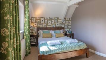 A bedroom with a wooden bed, green curtains, a patterned wall, and a nightstand with a lamp.