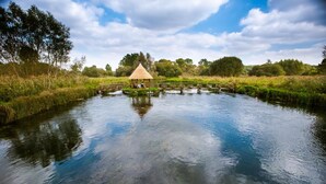 A tranquil riverside setting with a gazebo and a bridge over the water. - The Peat Spade Inn (Stockbridge)