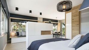 Una camera da letto moderna con un letto grande, una zona salotto integrata e vista sull'esterno.