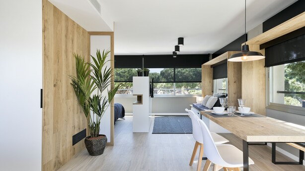 Una cucina moderna con un tavolo da pranzo in legno, sedie bianche e un'ampia finestra che offre vista sull'esterno.