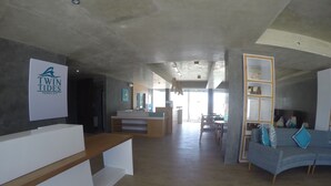 A spacious hotel lobby with a reception desk, a seating area with a sofa and chairs, and a large window providing natural light. - Twin Tides Panglao (Panglao)