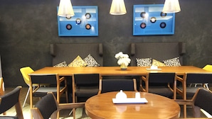 A conference room with a long table, round table, and chairs. There are wall-mounted lamps and a blue wall decoration. - Twin Tides Panglao (Panglao)