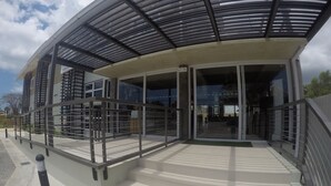 A modern building with a curved glass facade, outdoor seating area, and a covered entrance. - Twin Tides Panglao (Panglao)