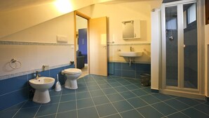 Un baño con suelo de azulejos azules, inodoro, bidé, lavabo y zona de ducha.