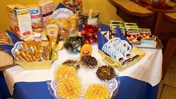 Uma mesa com diversos alimentos, incluindo waffles, chocolates e lanches.