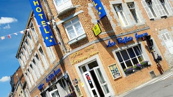 A hotel with a prominent 'HOTEL' sign, a 'B&B' sign, and a 'Les Reflets Journeys' sign.
