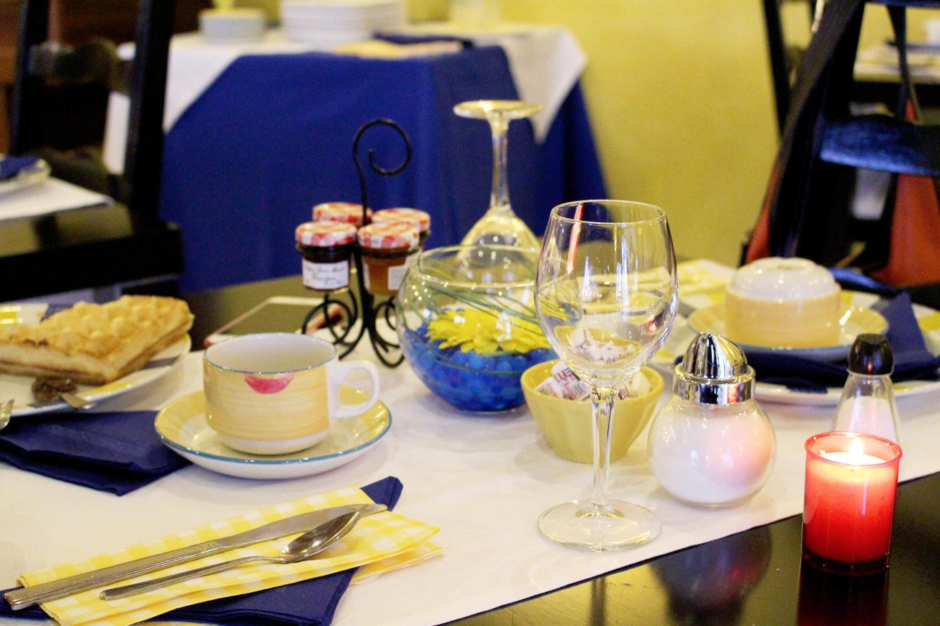 A table set with a dessert, a cup, a glass, a bowl, and a candle.