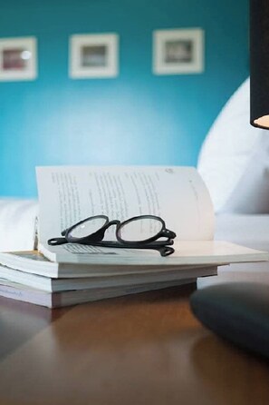 A stack of books with glasses on top, placed on a wooden surface. - Moonlight Cottage (Pa Klok)
