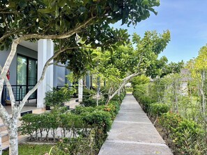 Stroll through lush gardens to a modern building with large windows and a balcony.