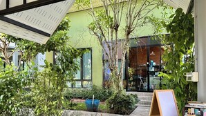 A courtyard with a glass table, a painting easel, and various plants. - Moonlight Cottage (Pa Klok)