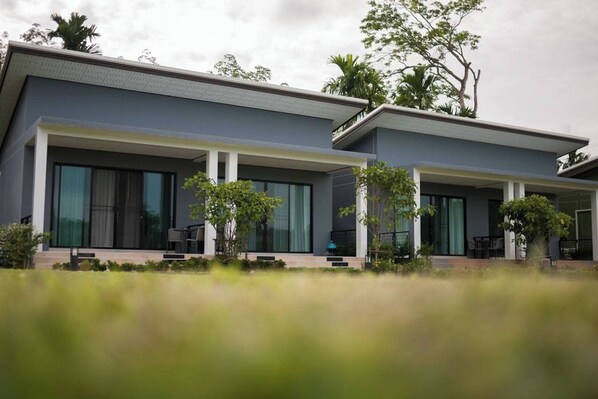 A modern two-story house with large windows, a covered porch, and a well-maintained garden. - Moonlight Cottage (Pa Klok)