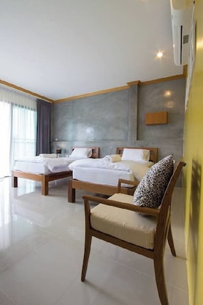Habitación de hotel con dos camas, una silla de madera, una mesita de noche y un aire acondicionado instalado en la pared.