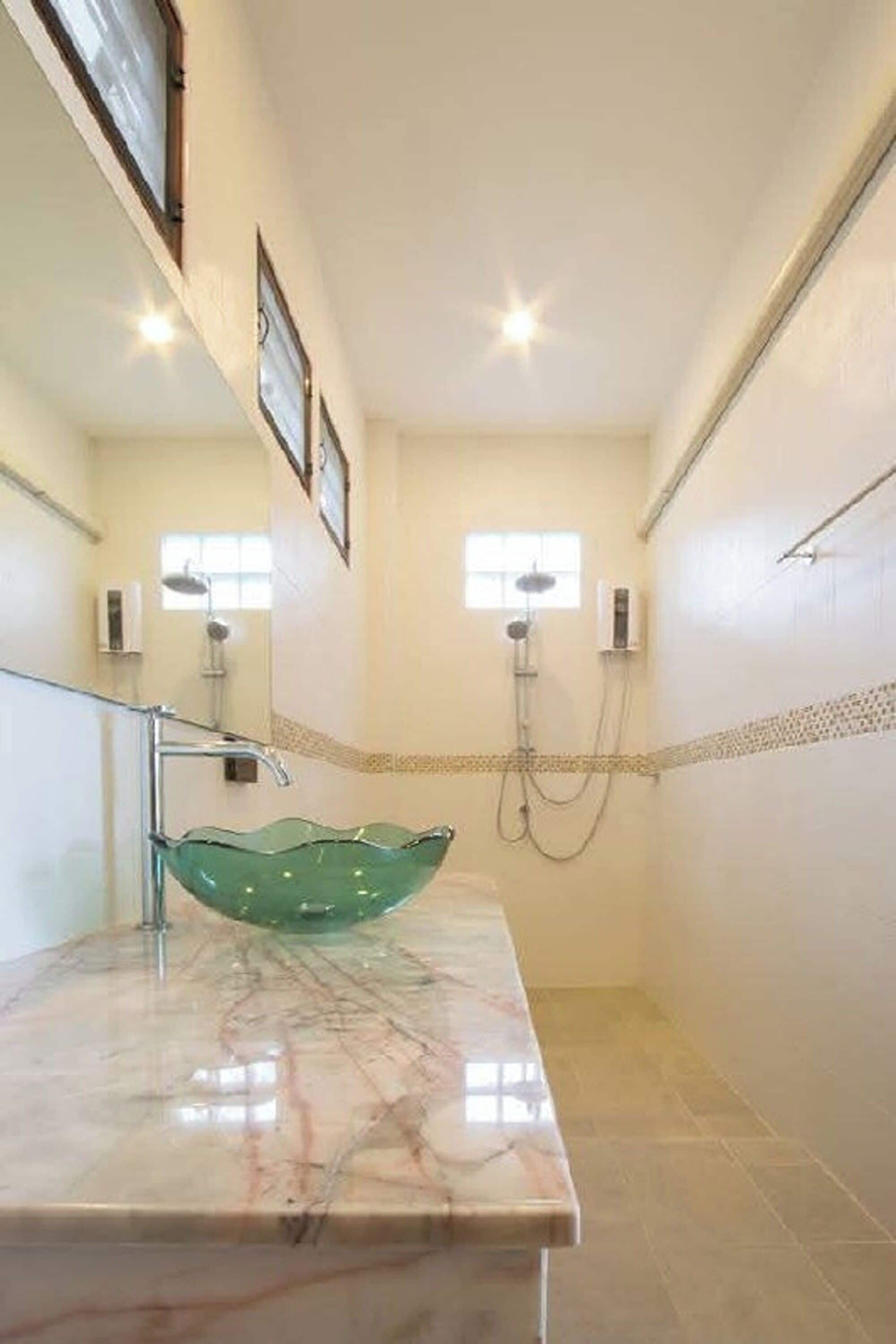 Un baño con un lavabo de vidrio, una ducha y un espejo.
