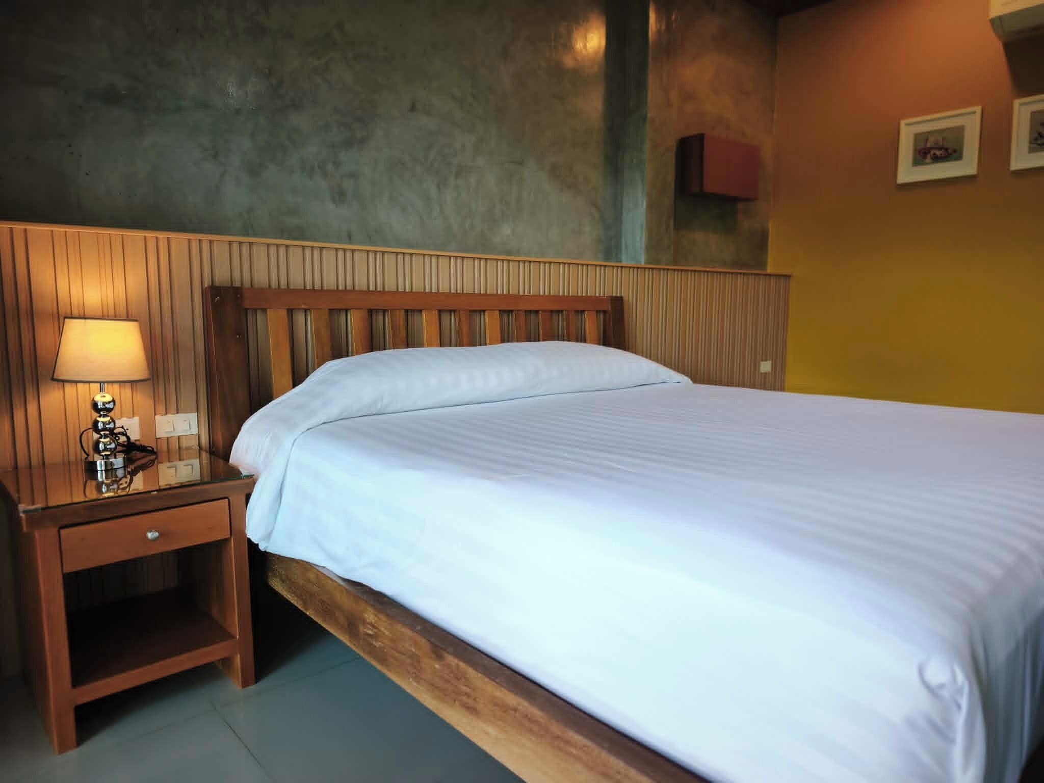 A single bed with a wooden headboard and a nightstand with a lamp.