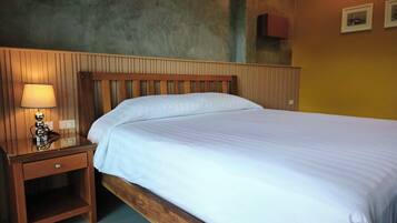 A single bed with a wooden headboard and a nightstand with a lamp.