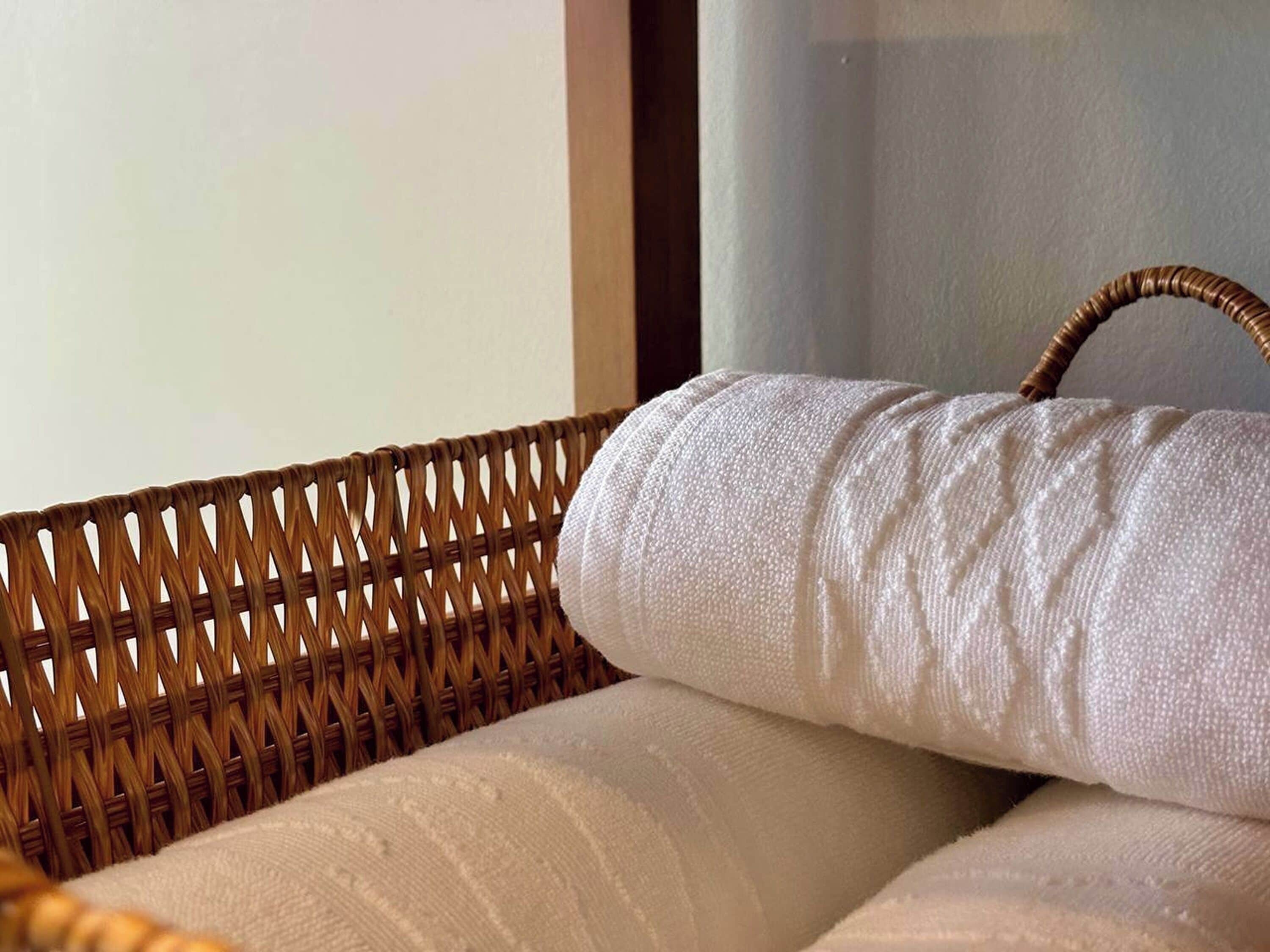 A wicker chair with a white cushion and a handle.