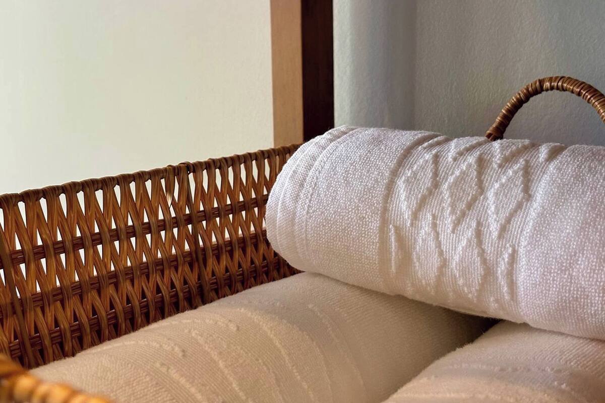 Una silla de mimbre con un cojín blanco y un asa.