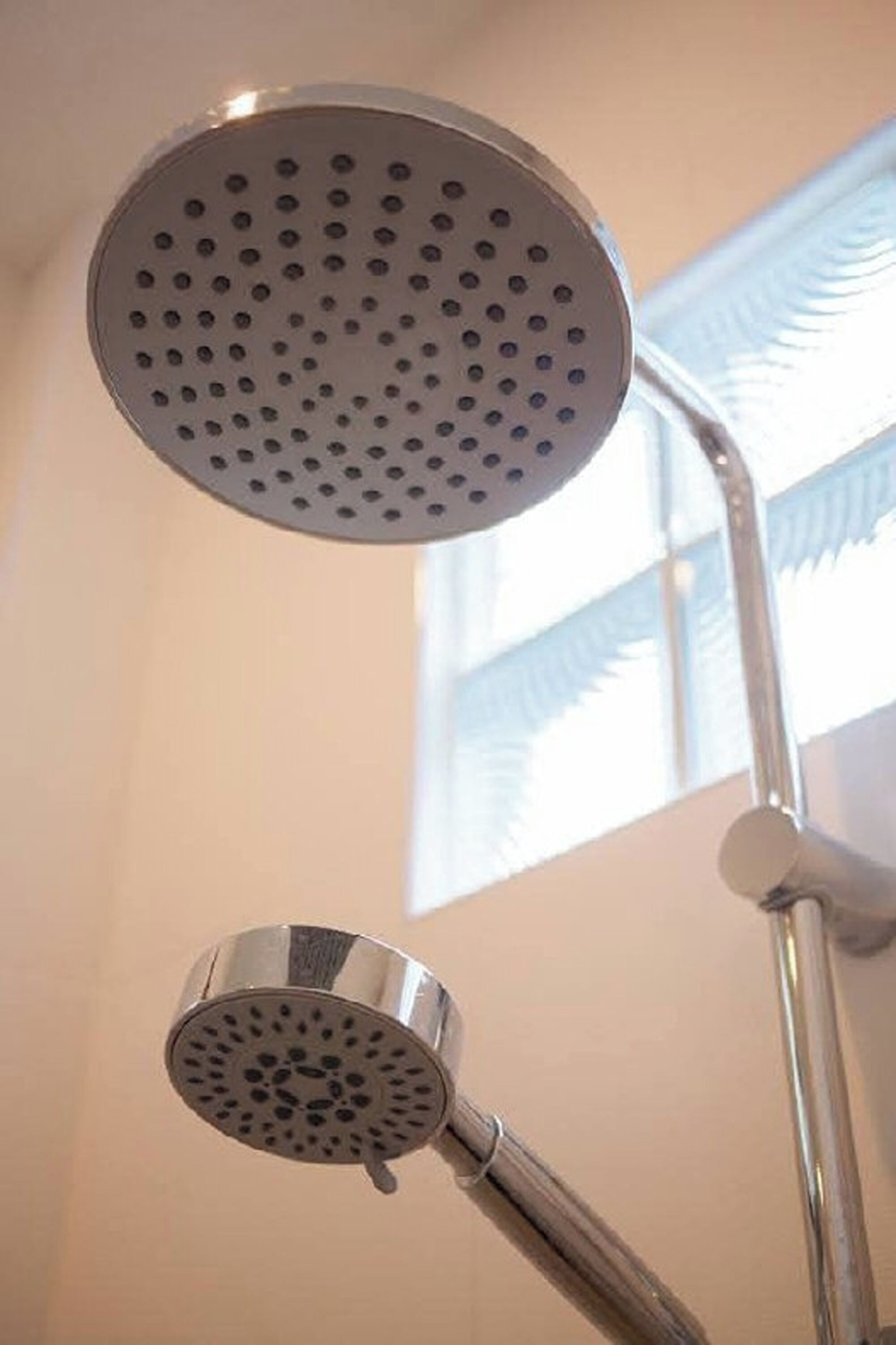 A shower with a circular head and a smaller handheld showerhead, both with multiple nozzles.