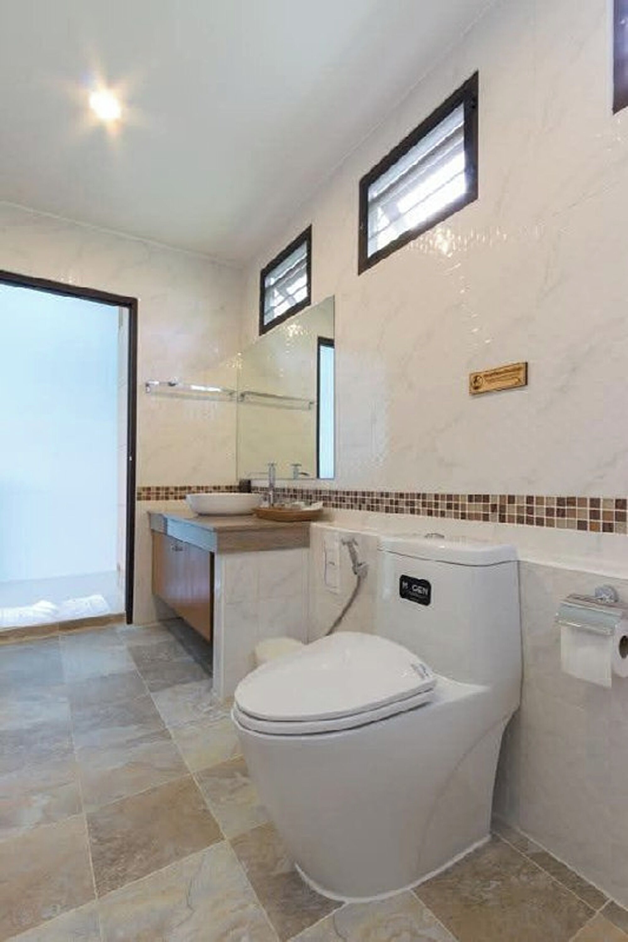 A bathroom with a toilet, sink, and mirror.