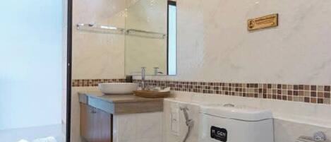 A bathroom with a toilet, sink, and mirror.