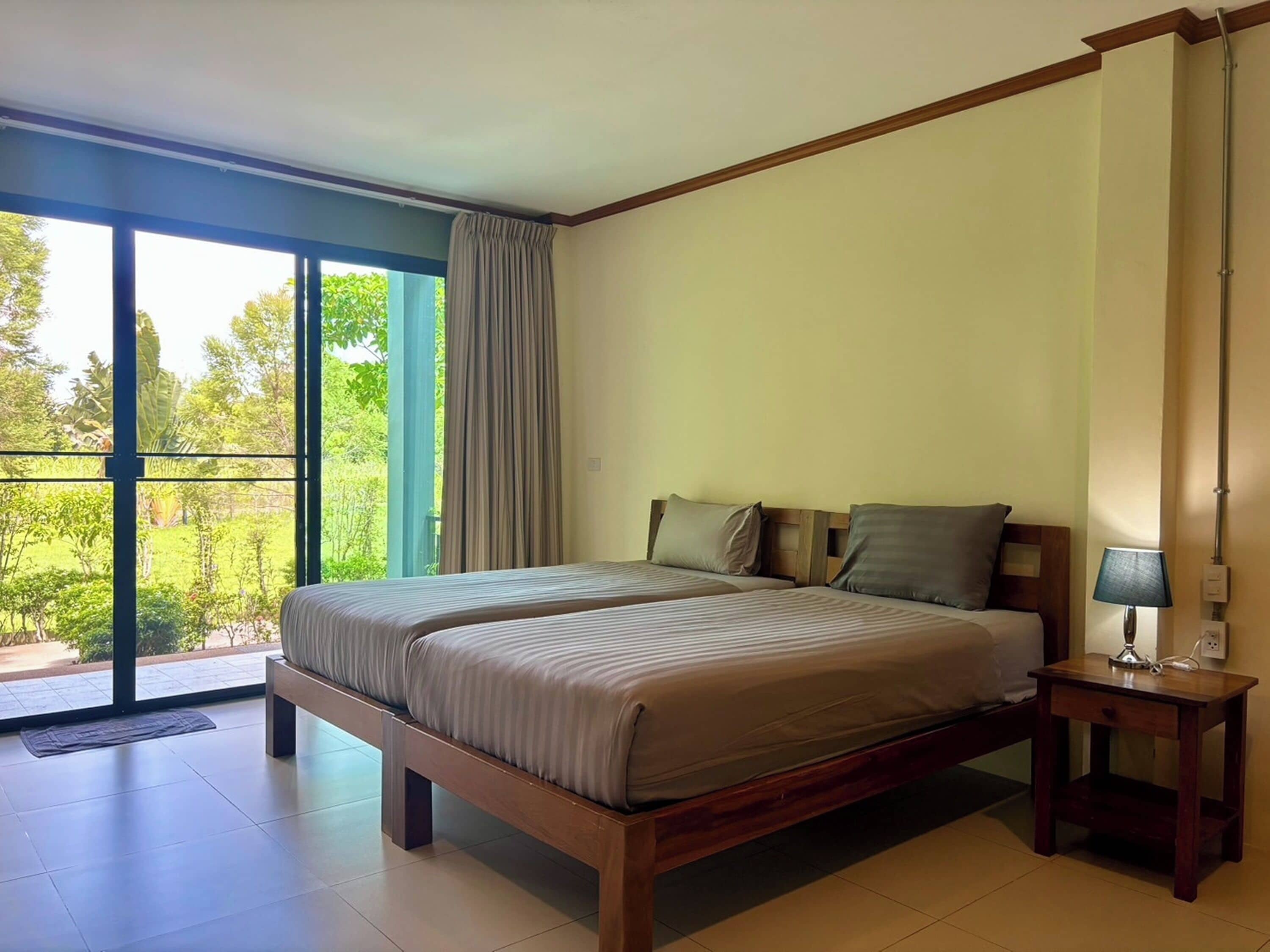 Une chambre avec un grand lit, une table de chevet et une vue sur la verdure.