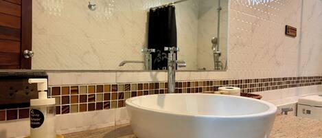 A bathroom with a large white sink, a handheld showerhead, and a towel rack.