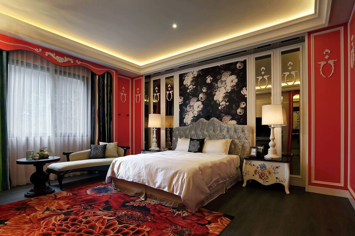 A hotel room with a large bed, a sofa, a small table, and a decorative rug.