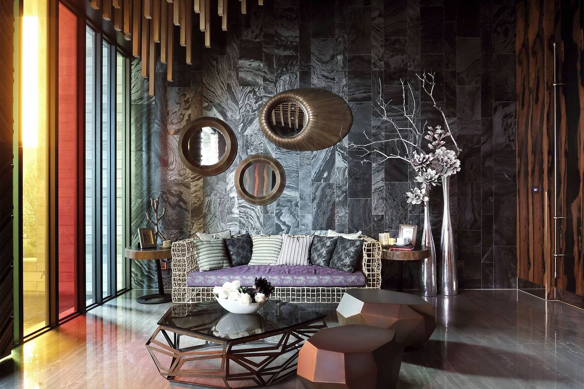 A modern living room with a sofa, coffee table, and decorative mirrors.