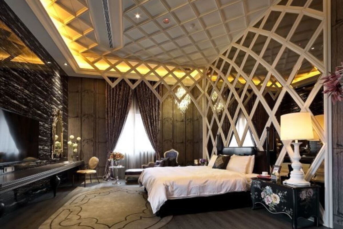 A bedroom with a bed, bedside tables, a mirror, and a chandelier.
