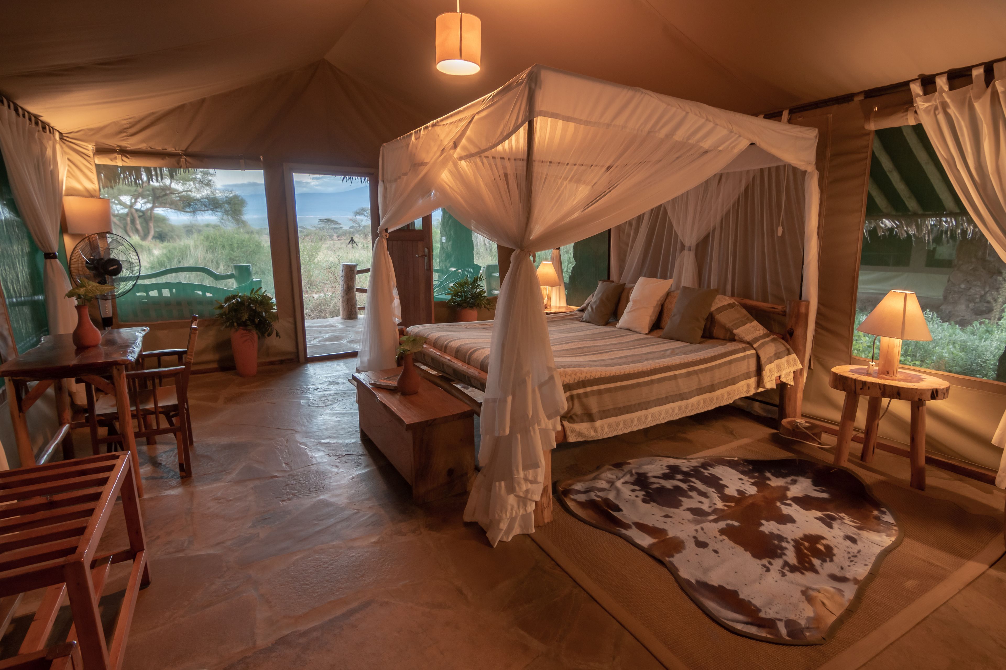 A tent-style bedroom with a canopy bed, wooden furniture, and a view of the outdoors.