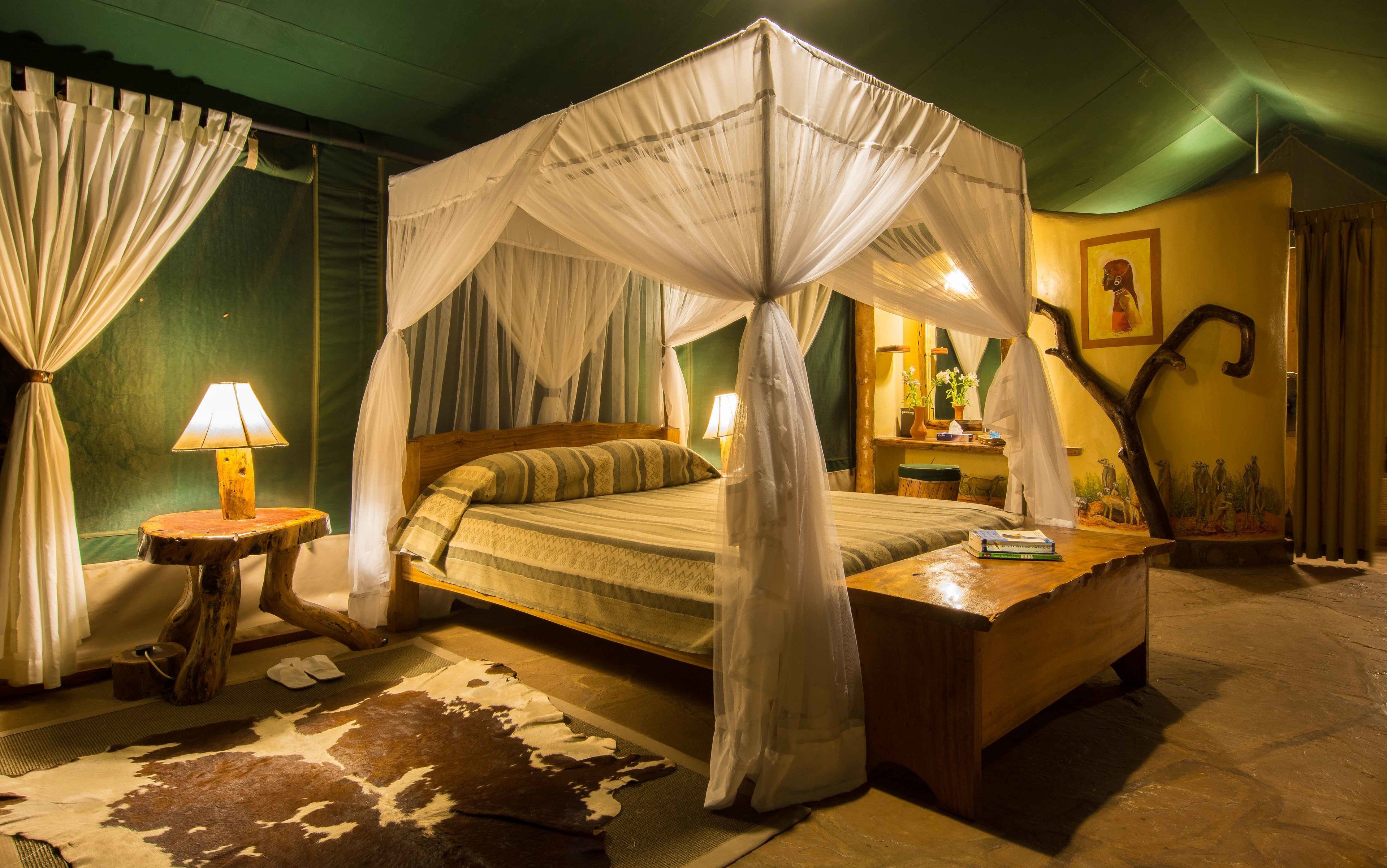 A four-poster canopy bed with a wooden headboard, a bedside table with a lamp, and a cowhide rug.
