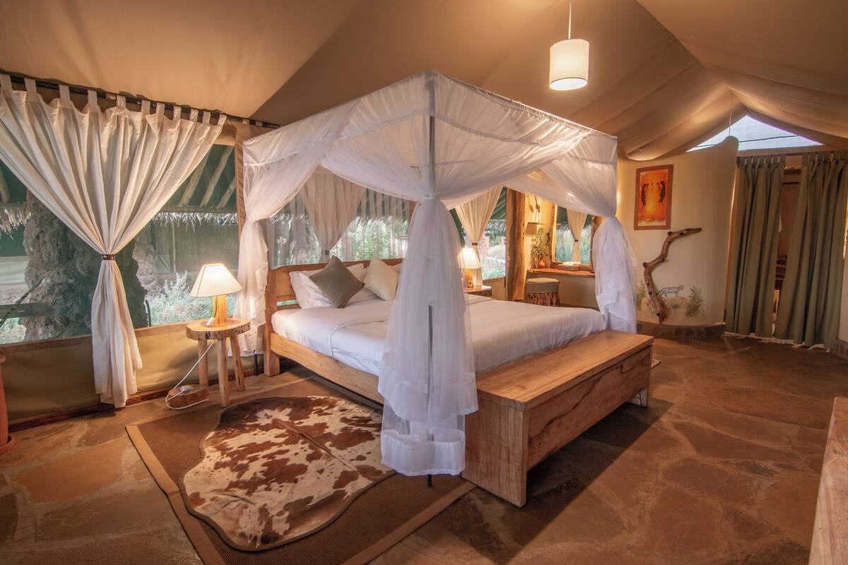 Ein Schlafzimmer mit Baldachinbett, Steinböden und Blick ins Freie.
