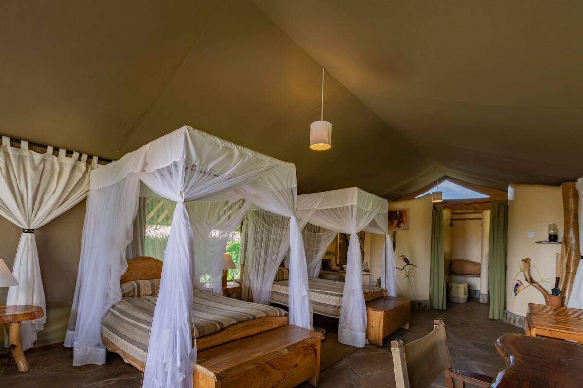 Ein Zimmer mit vier Betten, jedes mit Baldachin, Holmöbeln und einer Hängeleuchte.