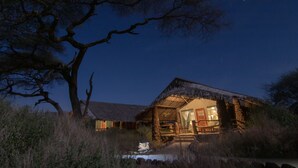 A thatched-roof building with a visible entrance and a staircase leading to the main door. - Kibo Safari Camp (Amboseli)