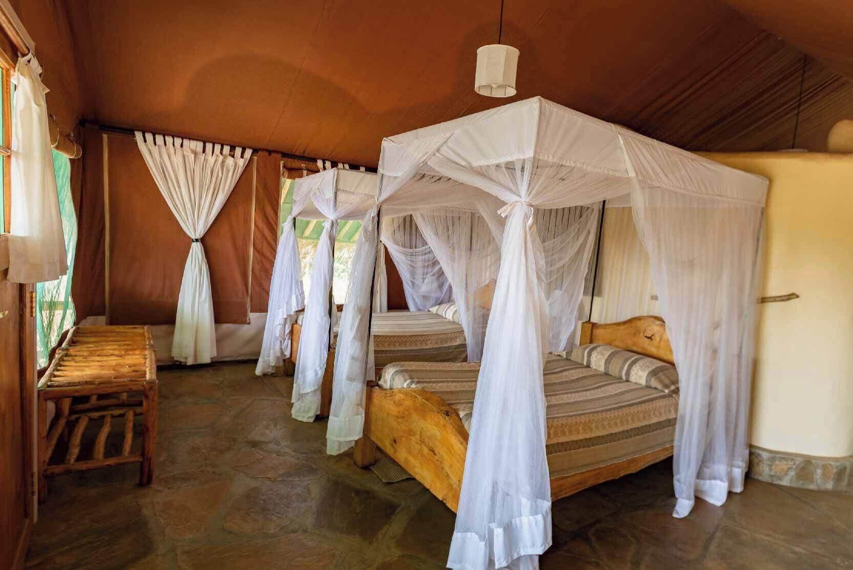 Um quarto com uma cama sob um dossel, um banco de madeira e piso de pedra.