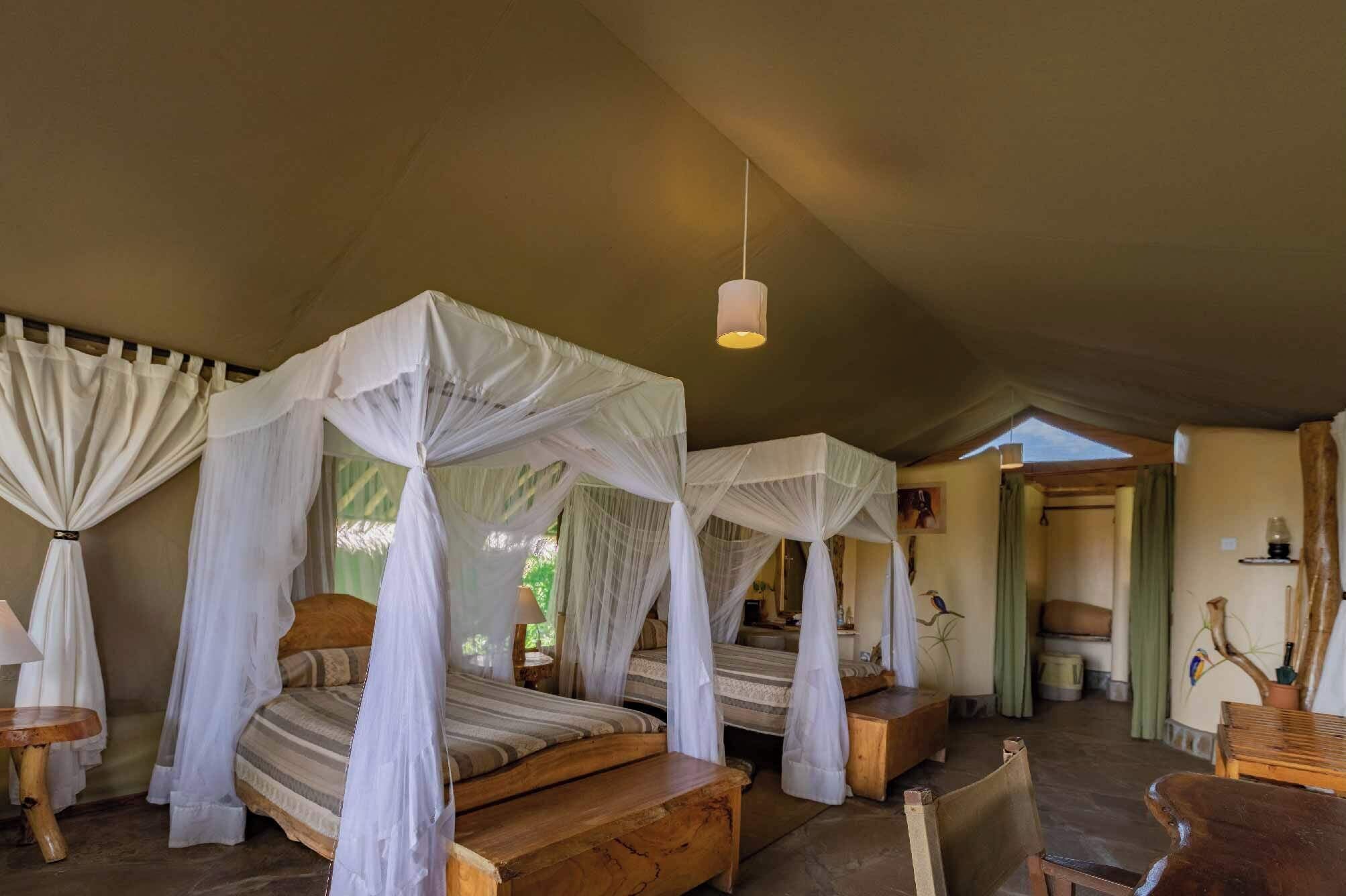 A room with four beds, each with a canopy, wooden furniture, and a hanging light fixture.