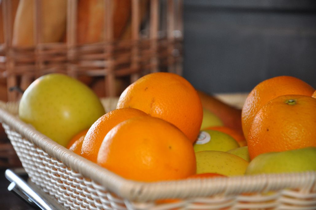 Una cesta de mimbre llena de naranjas y manzanas.