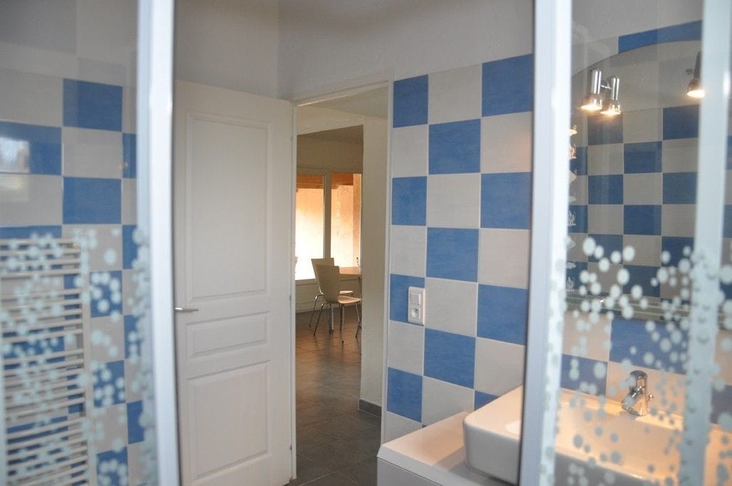 A bathroom with checkered blue and white tiles, a white sink, and a glass shower enclosure.