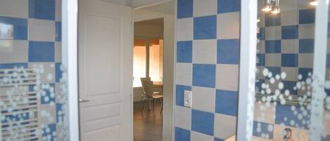 A bathroom with checkered blue and white tiles, a white sink, and a glass shower enclosure.