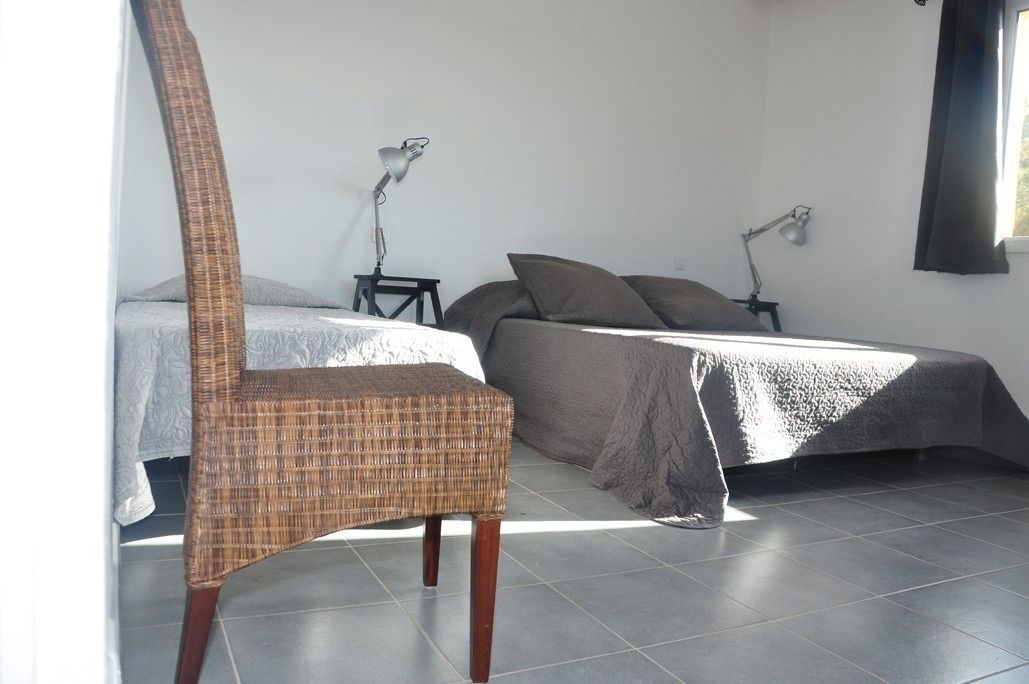 A bedroom with a bed, two bedside tables, a chair, and a window.