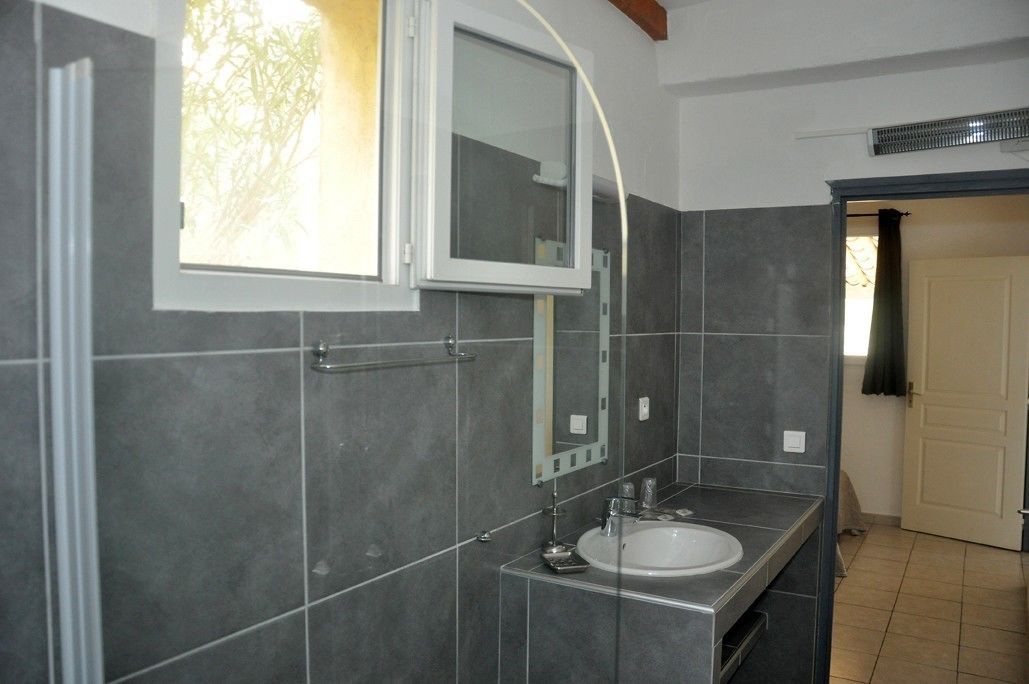 A bathroom with a large mirror, a sink, and a window.