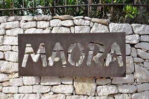 Un muro de piedra con un letrero metálico que dice "MAORA".